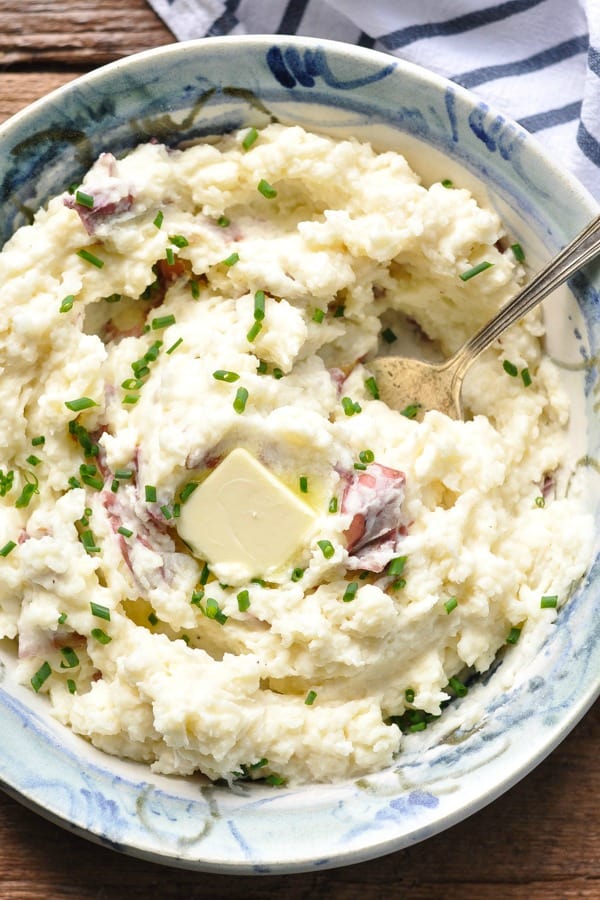 Close overhead image of a bowl of mashed red potatoes with cream cheese and butter on top