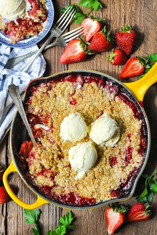 Shot of a strawberry crisp recipe baked in a cast iron skillet on a wooden table
