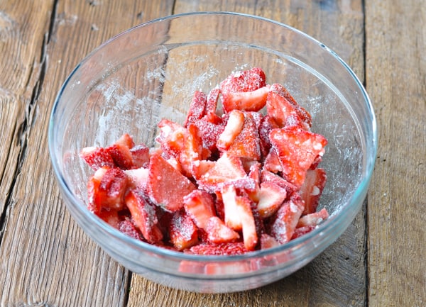 Process shot of stirring together fruit for strawberry crisp recipe