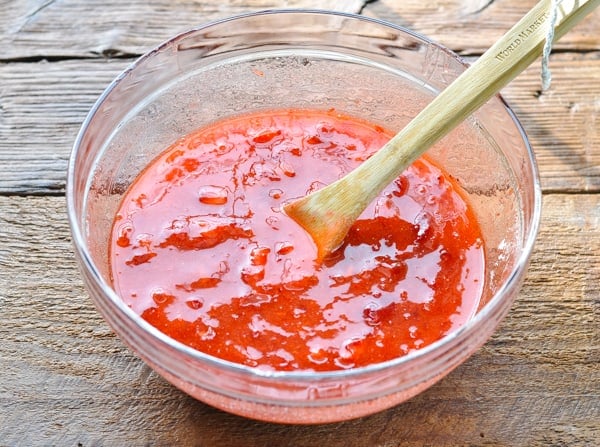 Stirring strawberry jam in a glass mixing bowl