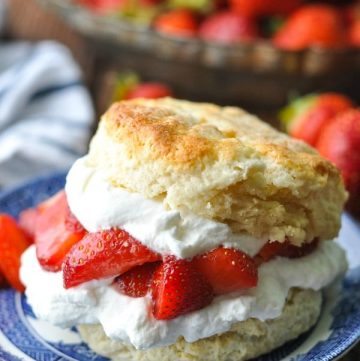 Close up image of an old fashioned strawberry shortcake recipe served on a plate with fresh berries in the background