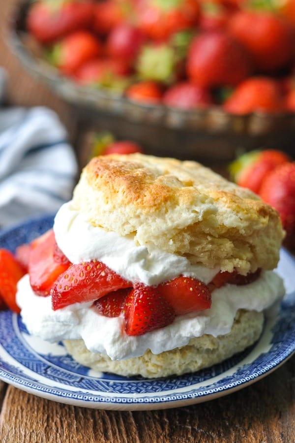 Close up image of an old fashioned strawberry shortcake recipe served on a plate with fresh berries in the background