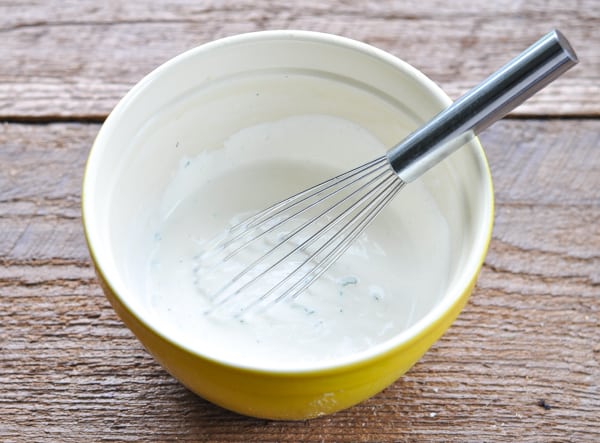 Ranch dressing for wedge salad in a yellow bowl with whisk