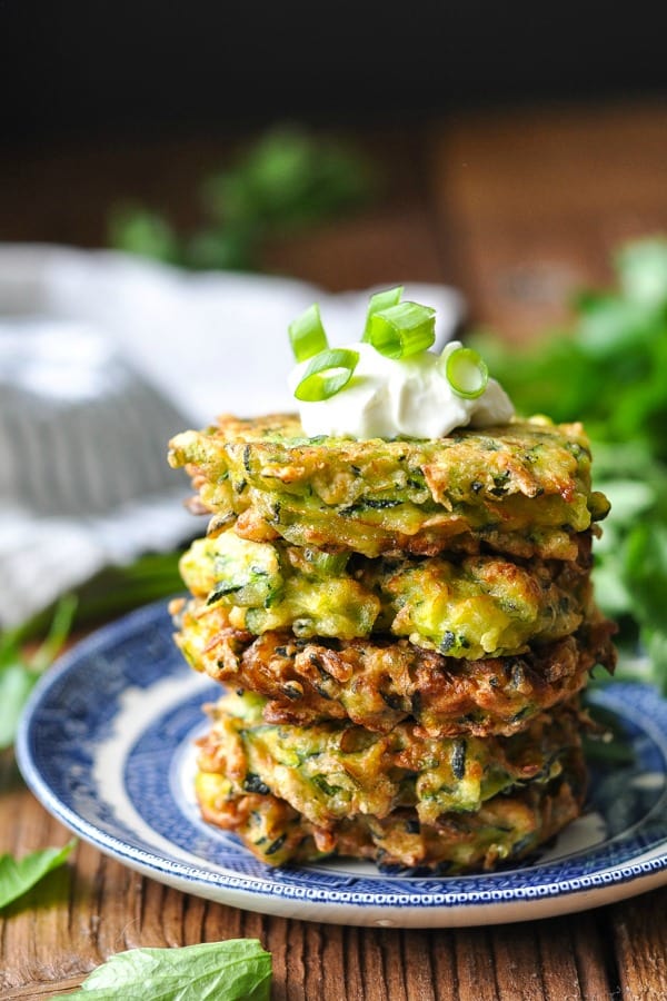 Stack of zucchini fritters with sour cream on top