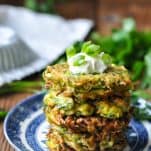 Front shot of a plate of zucchini fritters served with sour cream and chives