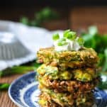 Front shot of zucchini pancakes piled high on a blue and white plate
