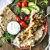 Square overhead image of Greek chicken souvlaki with a side of tzatziki.