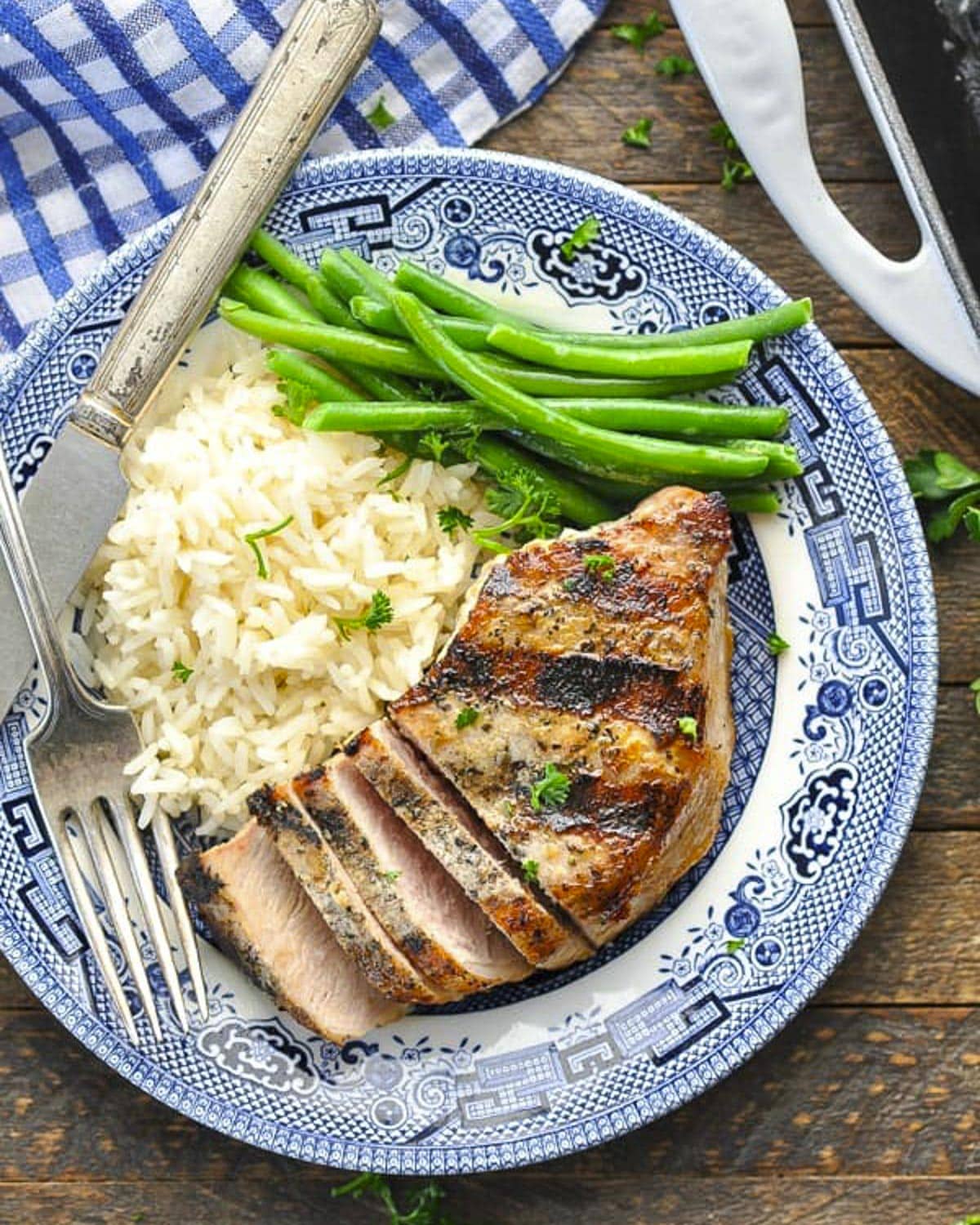 Overhead shot of grilled pork chop on a blue and white plate.