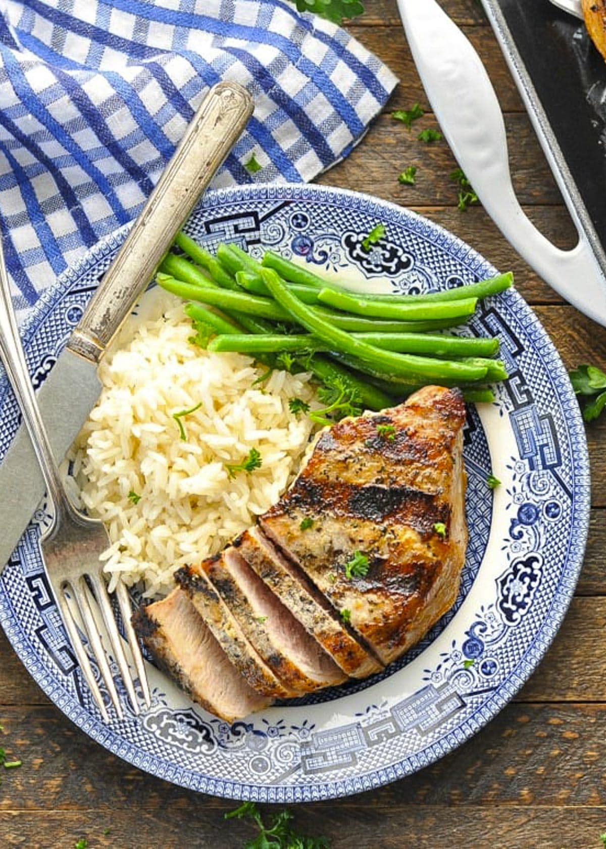Overhead image of a plate of grilled pork chops with rice and green beans.