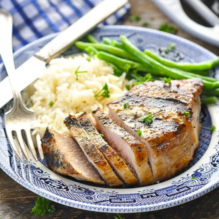 Square side shot of grilled pork chop recipes on a blue and white plate.