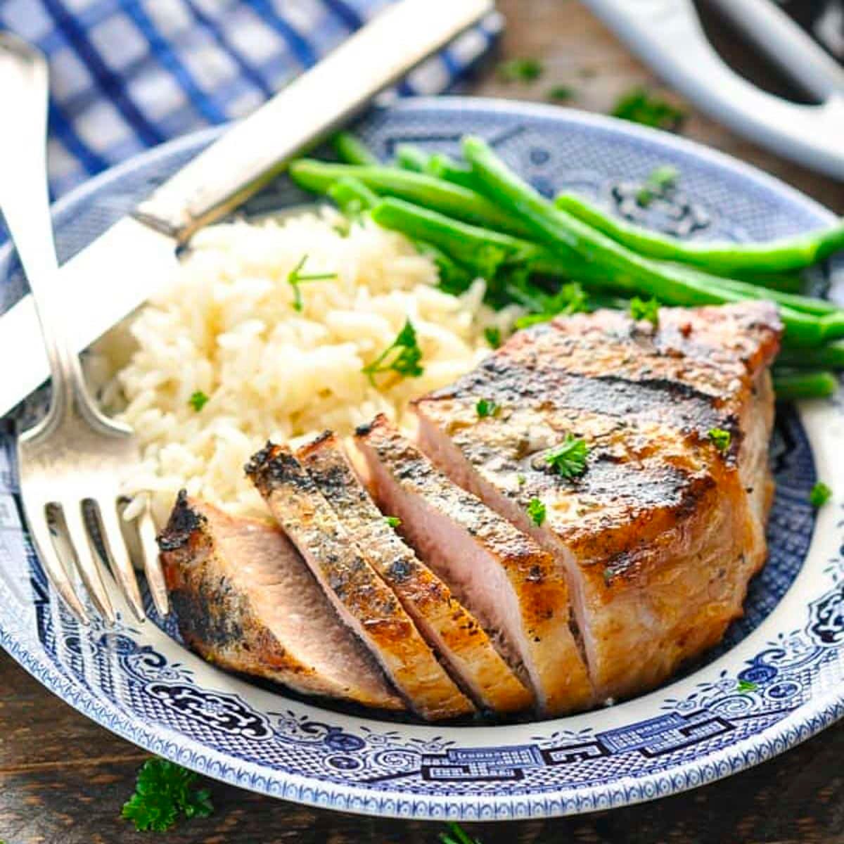 Square side shot of grilled pork chop recipes on a blue and white plate.
