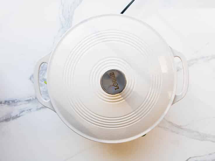 Covering a skillet of sauteed spinach with a lid.