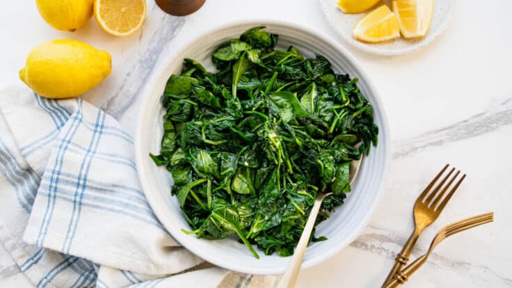 Horizontal overhead shot of a white bowl full of sauteed spinach.