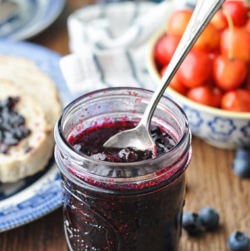 Front shot of a spoon in a jar of homemade blueberry jam