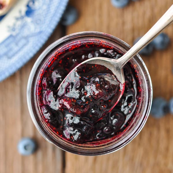 Overhead close up shot of a spoon in a jar of blueberry jam