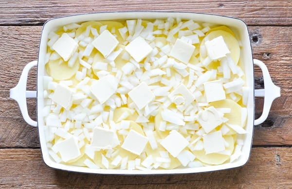 Onions and butter on top of potatoes in a casserole dish