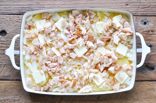 Diced chicken on top of potatoes and onions in a casserole dish