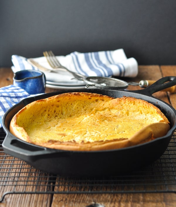 Front shot of a baked german pancake in a cast iron skillet on a cooling rack
