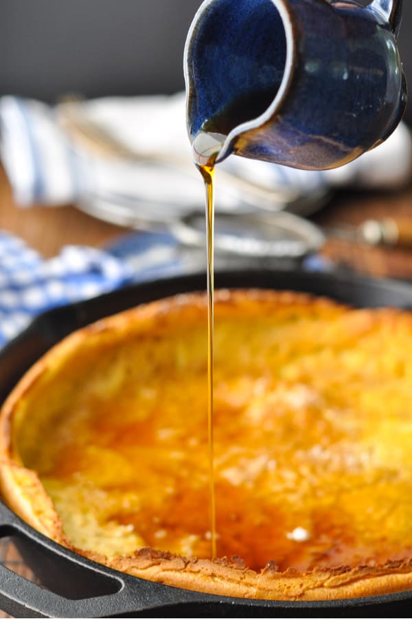 Close up front shot of maple syrup pouring on a Dutch Baby Pancake