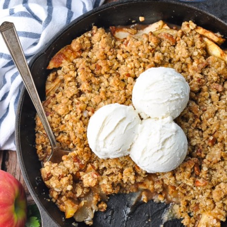 Close overhead shot of an easy apple crisp baked in a cast iron skillet with vanilla ice cream on top