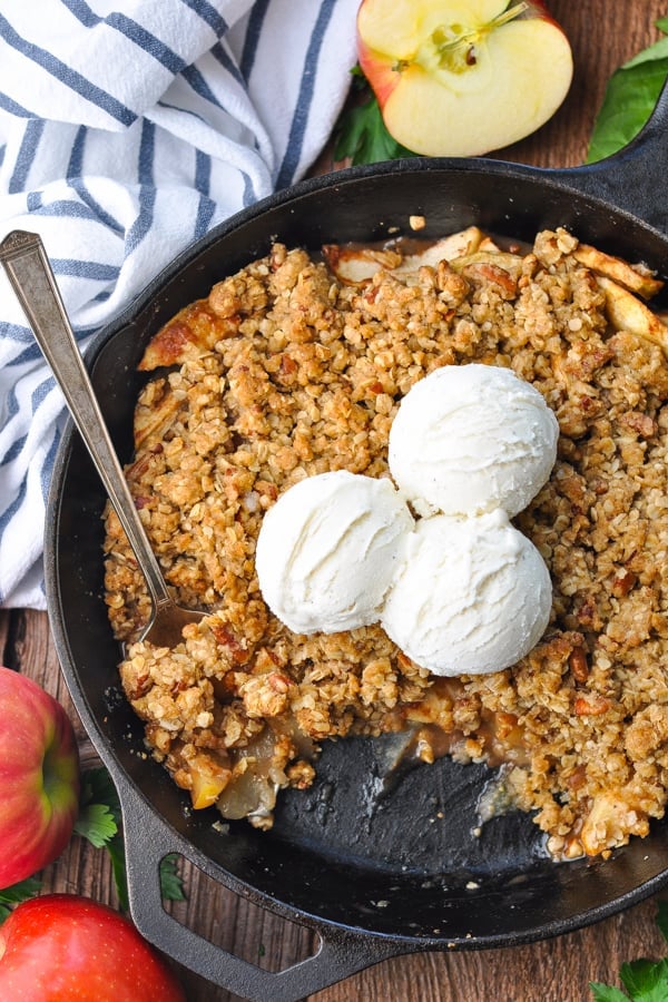 Close overhead shot of an easy apple crisp baked in a cast iron skillet with vanilla ice cream on top