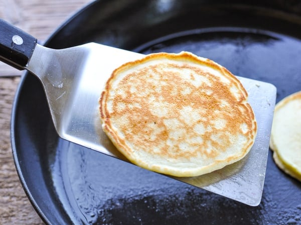 Spatula flipping buttermilk pancakes in a cast iron skillet