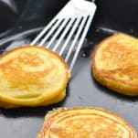 Horizontal shot of cornmeal griddle cakes in a cast iron skillet