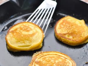 Horizontal shot of cornmeal griddle cakes in a cast iron skillet