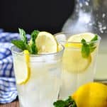 Two glasses and a pitcher of homemade lemonade on a wooden table