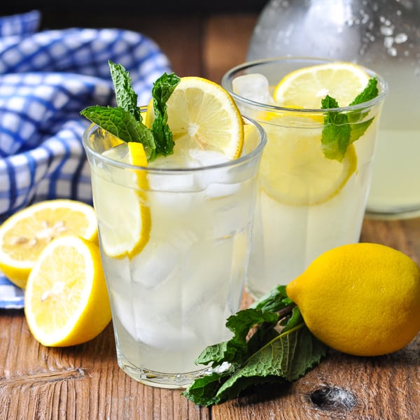 Square shot of two glasses of homemade lemonade with mint and lemons nearby