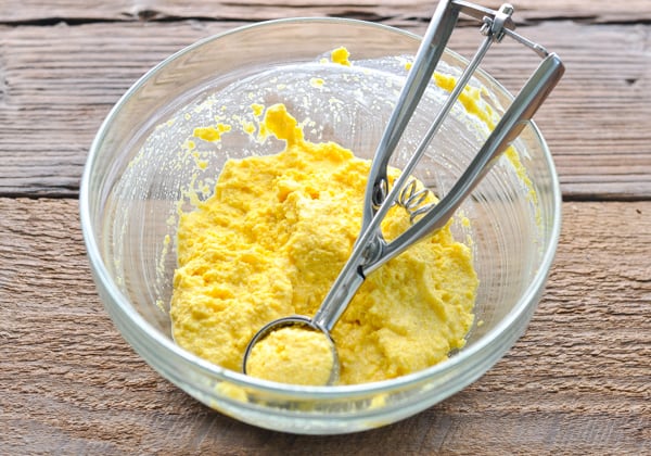 Cornmeal batter for hush puppies recipe in a glass bowl with a scoop