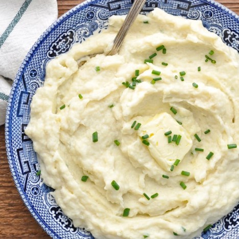 Close overhead image of a serving spoon in a bowl of mashed cauliflower