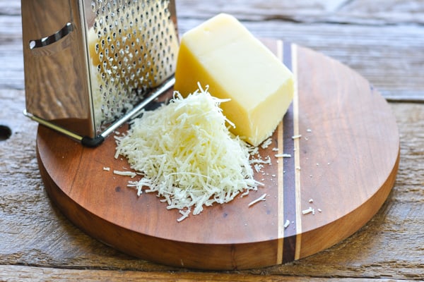 Grated fresh Parmesan cheese on a wooden cutting board