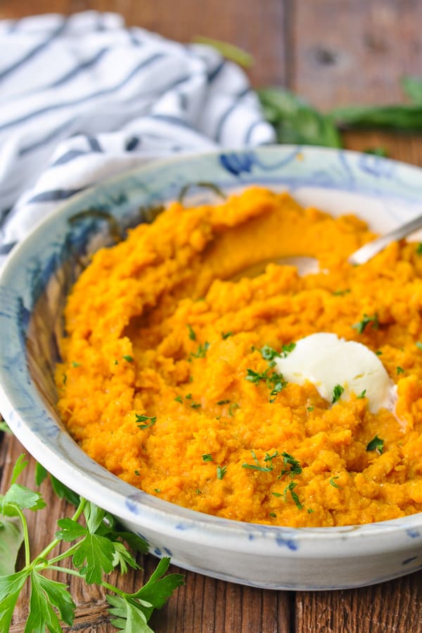 Side shot of a bowl of homemade mashed sweet potatoes with a spoon in the bowl for serving