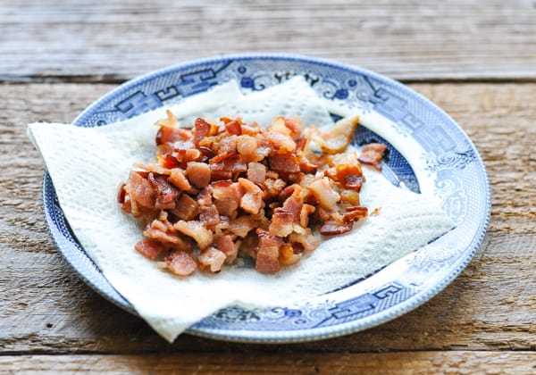 Cooked, chopped bacon draining on paper towels on a plate