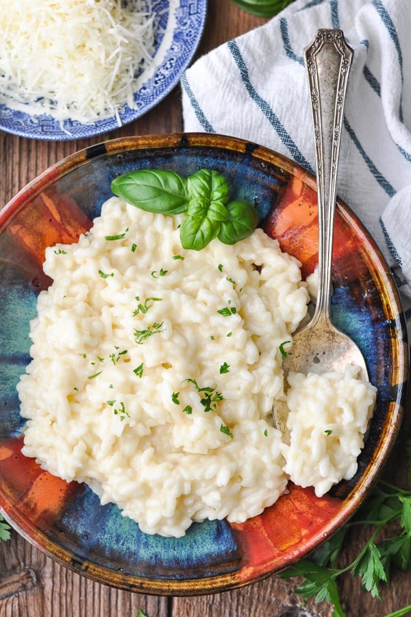 Close overhead shot of a bowl of creamy risotto with a silver serving spoon