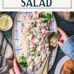 Hands holding a plate of seafood salad with text title box at top