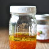 Ingredients for pepper jelly vinaigrette recipe in a glass mason jar.
