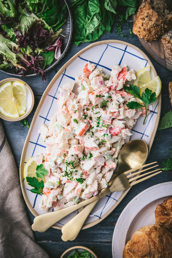 The best seafood salad recipe on a blue and white plate with parsley and lemon wedges for garnish