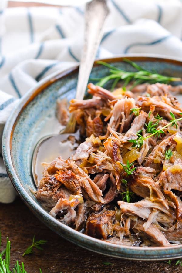 Front side shot of a bowl of shredded pork with silver serving spoon