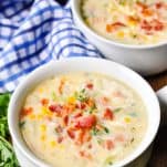 Front shot of two bowls of corn chowder with bacon on a wooden table