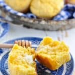Corn muffin on a plate slathered in butter and drizzled with honey