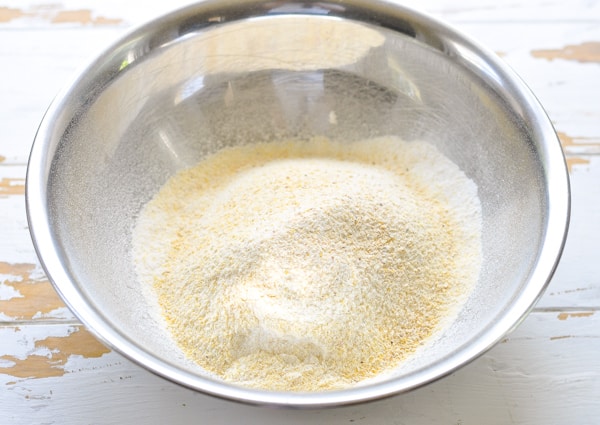 Dry ingredients for corn muffins in a metal mixing bowl