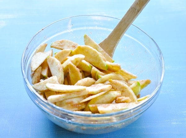Peeled and sliced apples with spices in a glass mixing bowl