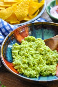 Close up front shot of an easy guacamole recipe served in a colorful bowl
