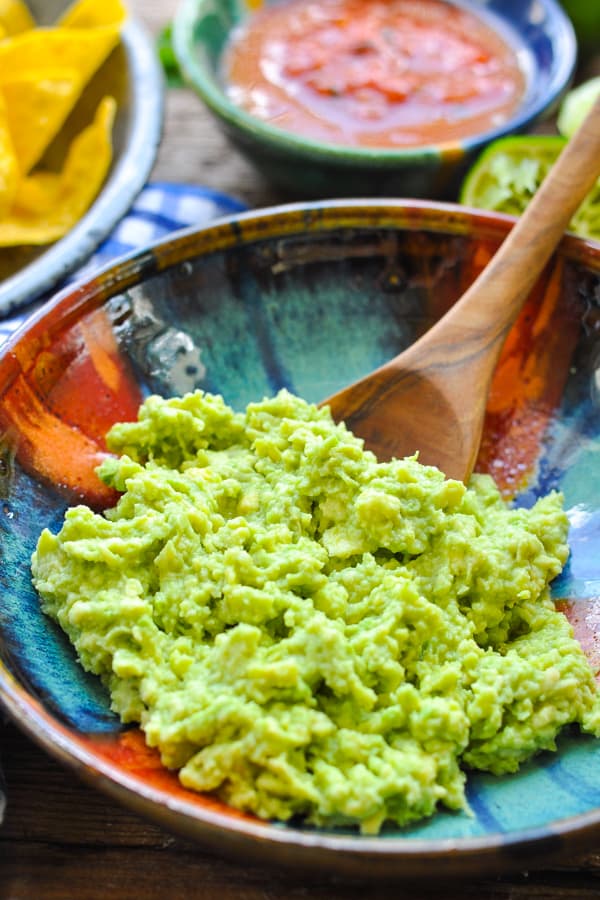 Side shot of an easy guacamole recipe served in a bowl with a wooden spoon