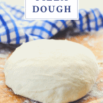 Front shot of a ball of easy homemade pizza dough on a wooden board with text title at top