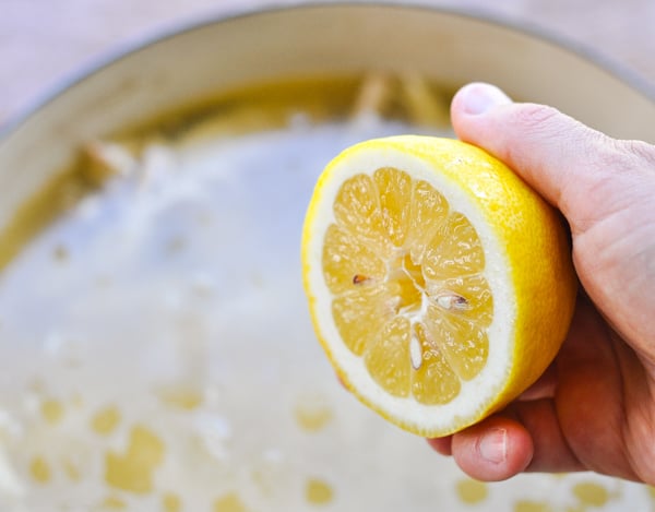 Squeezing lemon juice into a pot of chicken and noodles
