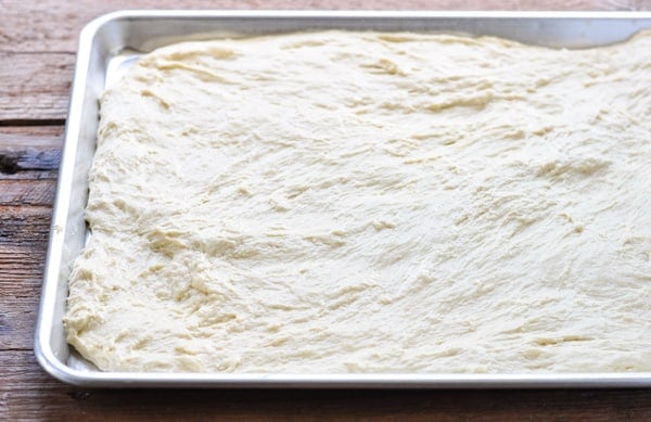 Spreading focaccia dough on a baking sheet