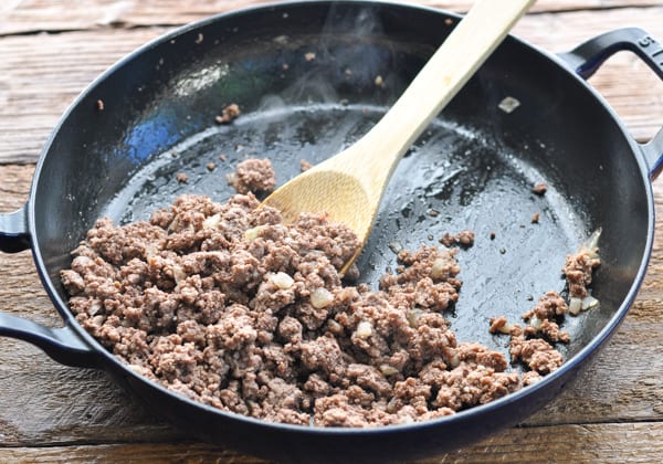Cooked ground beef with garlic and onion in a cast iron skillet